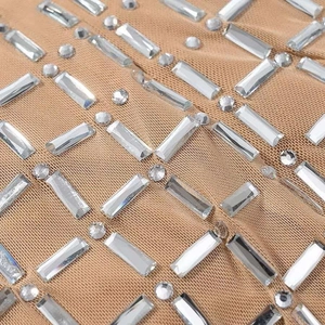Détail d'une robe en maille nude avec des strass brillants disposés en grille géométrique
