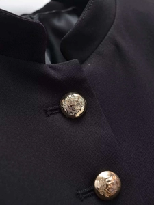 Detailed macro view of the stand-up collar and embossed gold crest buttons on black jacket