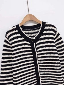 Dettaglio del cardigan a righe bianche e nere con bottoni strutturati e girocollo
