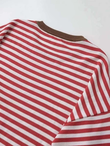 Détail d'un pull rayé rouge et blanc avec col rond en maille côtelée marron contrastée