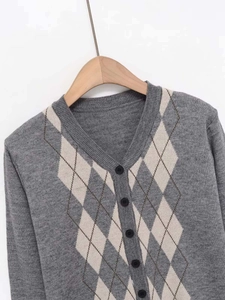 Macro detail of Argyle knit pattern and classic round black buttons on V-neck cardigan