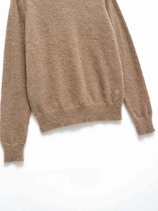 Detailed macro view of the soft tan knitted wool sweater with ribbed hem and cuffs