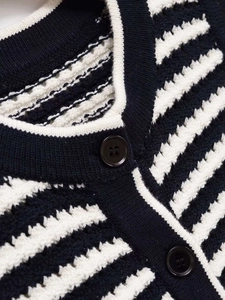 Close-up of black and white striped knit vest with premium resin buttons and round neck