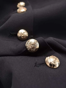 Detailed close-up of textured black fabric with decorative embossed gold metal buttons