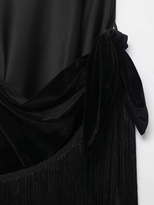 Detailed close-up showing satin fabric, velvet knot, and long black fringe trim on a dress