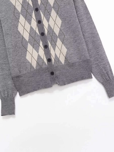 Detail of grey argyle knit cardigan featuring resin buttons and ribbed cuffs texture