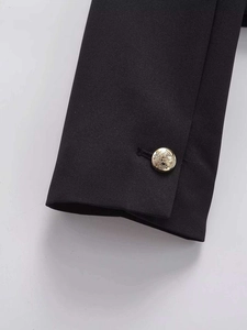 Close-up of black jacket cuff with embossed gold metal button featuring eagle crest
