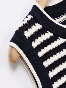 Detail of classic black and white striped knit vest with white ribbed neckline edging