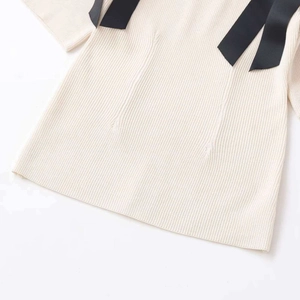 Chic cream ribbed knit top featuring elegant black bow shoulder straps and contrast details