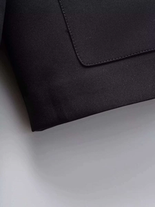 Detail of a black jacket showing premium woven fabric texture and precise pocket stitching