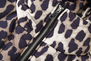 Close-up of leopard print puffer jacket detailing silver metal zipper and fabric texture