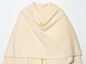 Close-up of cream wool cape coat featuring a single round button and soft draped texture