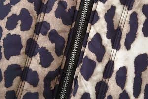 Macro view of leopard print fabric with silver metal zipper and reinforced stitching