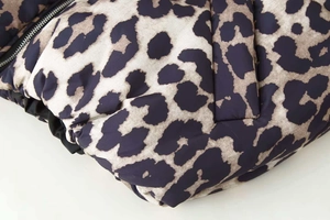 Detailed close-up of leopard print quilted winter jacket with metal zipper and stitching