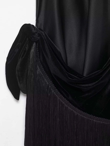 Close-up of elegant black velvet dress detailing with silk satin knot and fine fringe