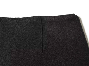 Dettaglio macro della trama in lana nera e delle cuciture rifinite degli shorts