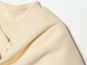 Detailed macro shot of soft cream wool fabric with a matching round white button