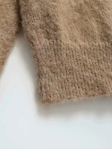 Detailed macro view of the dark camel ribbed cuffs on a plush v-neck knit sweater