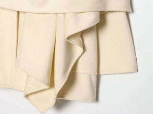 Detail shot of layered cream wool coat fabric featuring elegant draped texture and lining