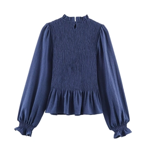 Detail view of navy blue smocked blouse with ruffle collar and lantern sleeves