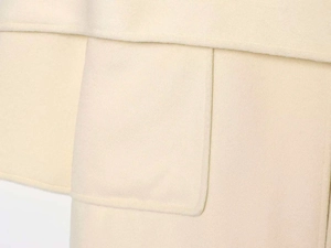 Close-up of ivory wool coat featuring a large patch pocket and precise stitching details