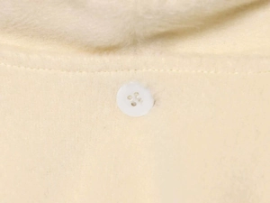 Detail view of cream-colored fleece coat featuring a white four-hole resin button and soft trim