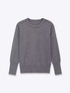 Detailed macro view of the knitted grey sweater featuring decorative golden shoulder buttons