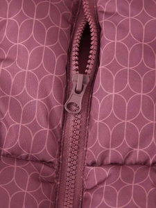 Détail macro du tissu matelassé bordeaux à motifs géométriques et fermeture éclair assortie