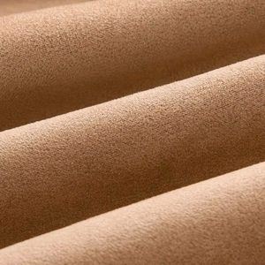 Detailed close-up of soft camel faux suede fabric texture with natural elegant folds