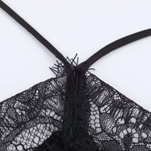 Detailed macro view of black lace stitching and thin elastic straps on a halter dress