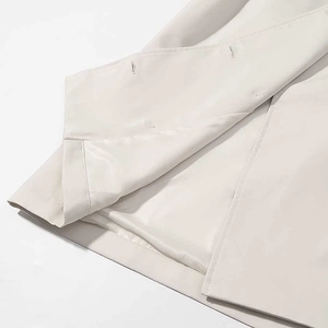 Detailed view of the double-breasted buttonholes and fine stitching on a beige trench coat