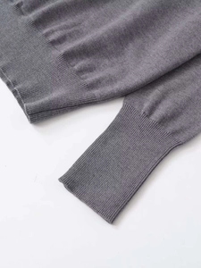 Close-up of gray knit sweater showing ribbed cuffs and hem with fine knit texture