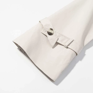 Close-up of trench coat cuff with adjustable strap and premium dark resin button detail