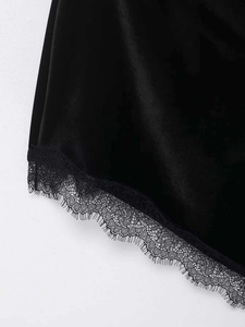Detailed close-up of luxurious black velvet dress featuring delicate floral lace hem