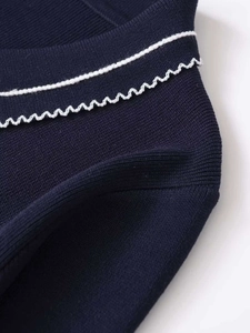 Detailed macro view of navy knit fabric with white wavy lace trim and ribbed texture