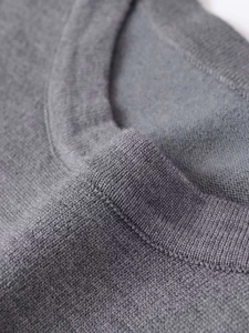 Detail of gray knitted sweater showing fine fabric texture and round neckline finish