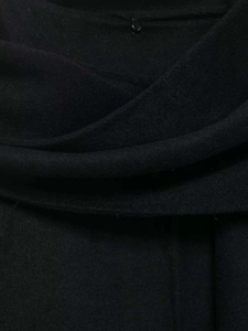 Close-up of premium black wool blend fabric texture with a small tonal button detail