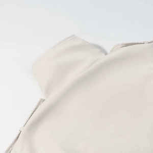 Detailed view of the refined stitching and buttoned shoulder strap on a beige trench coat