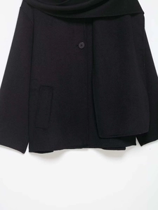 Close-up of black wool coat with matching scarf set and refined button detail