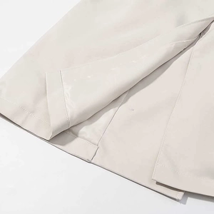 Detailed close-up of the double-breasted trench coat hem with elegant slit and smooth finish