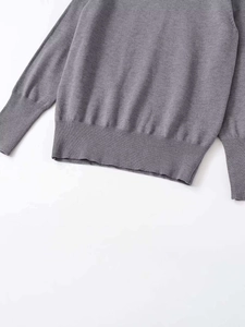 Close-up of ribbed cuffs and hem on a casual grey knitted sweater with fine knit texture