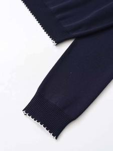 Close-up of navy blue knit sweater featuring ribbed cuffs and white scalloped lace trim