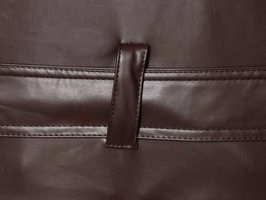 Détail de texture en similicuir marron foncé avec double couture précise et boucle de ceinture