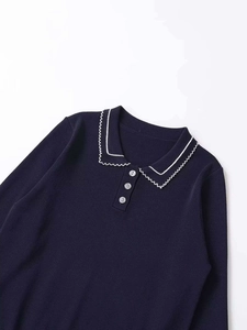 Detailed close-up of navy knit top featuring white scalloped collar and grey buttons