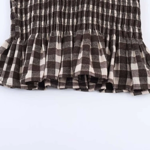 Detail of brown gingham fabric featuring smocking texture and ruffled hemline