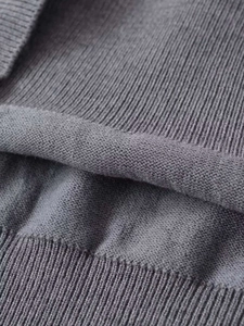 Detailed macro texture of grey knit fabric showing ribbed hem and soft weave patterns