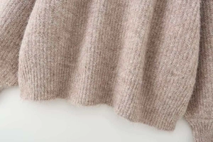 Macro detail of oatmeal knit sweater showing ribbed hem and fuzzy wool texture