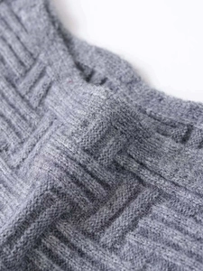 Macro shot of gray geometric jacquard knit fabric showing thick wool texture