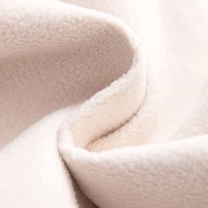 Détail du tissu polaire blanc cassé doux montrant la texture thermique d'hiver