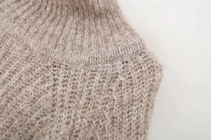 Detail view of oatmeal-colored knit sweater featuring ribbed collar and fluffy texture